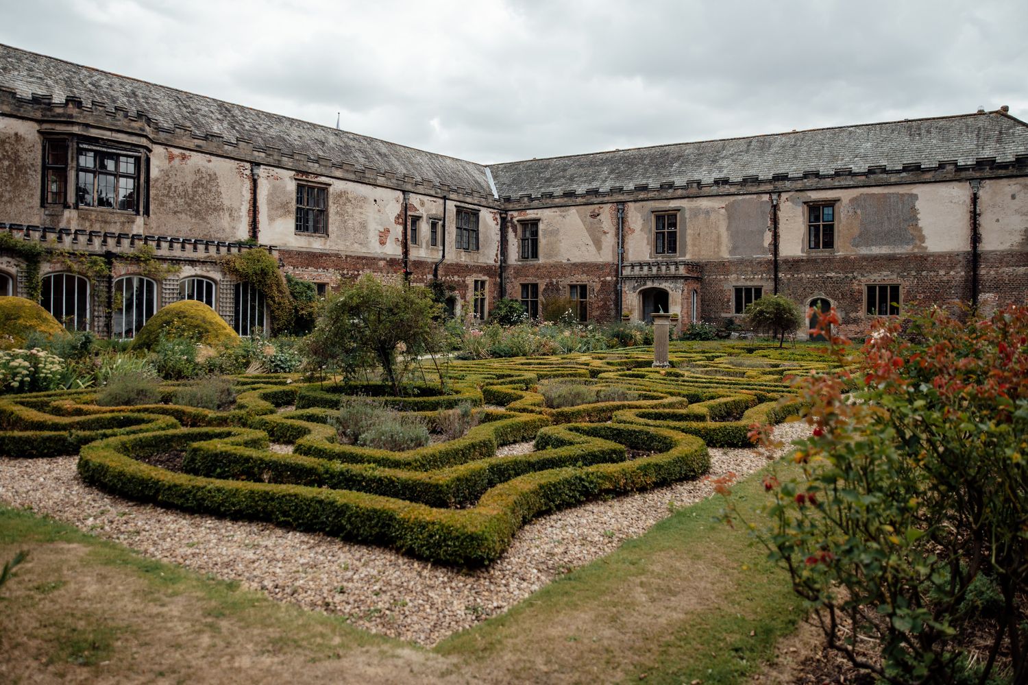 Aerial view of formal gardens and pathways surrounding a historic stone manor house.