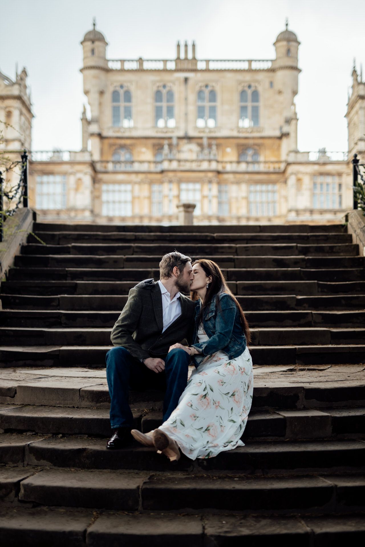 A couple shares an intimate moment on grand stone steps leading to a majestic classical building.