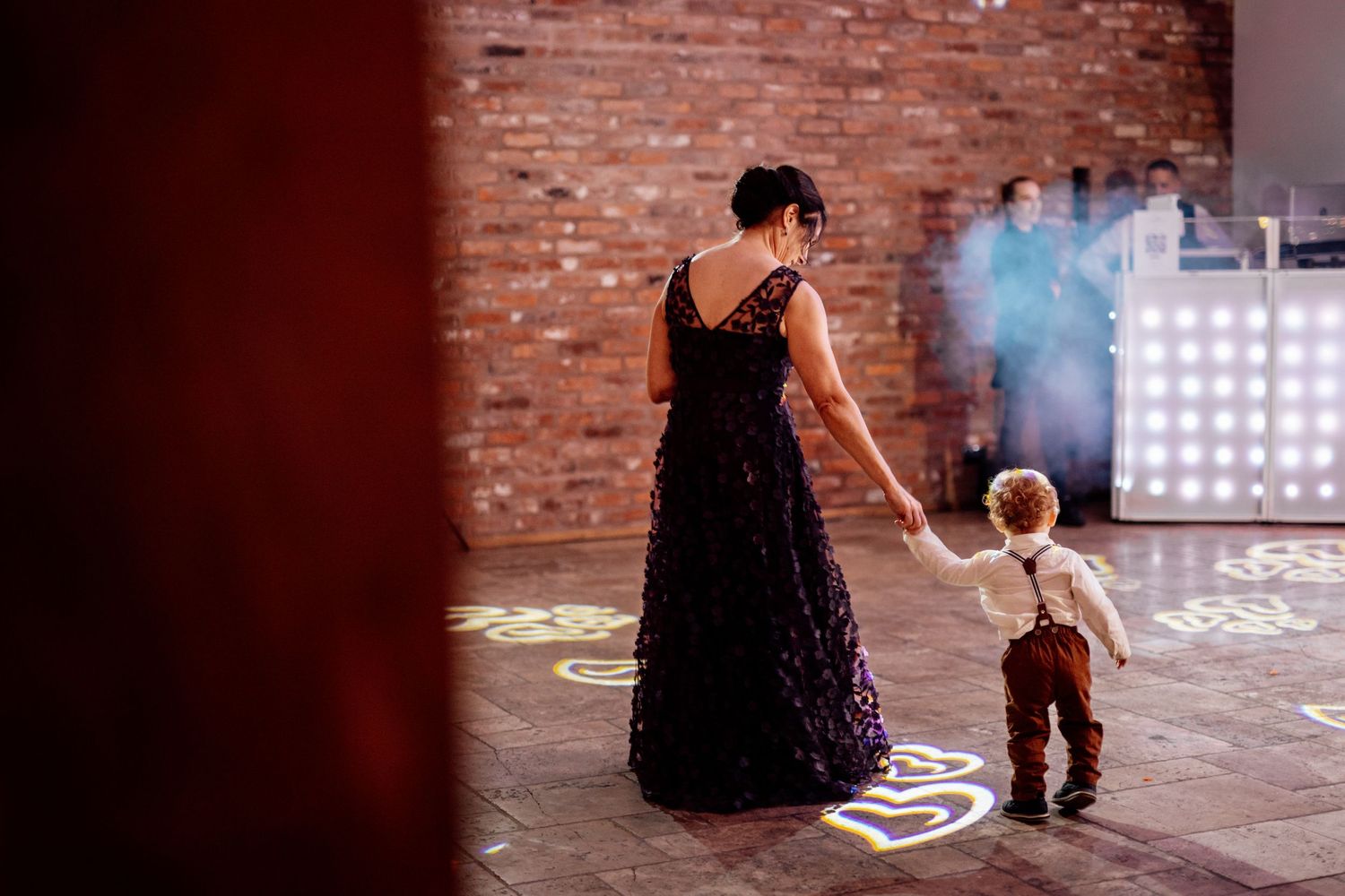 Child in formal wear playing on dance floor at wedding reception.