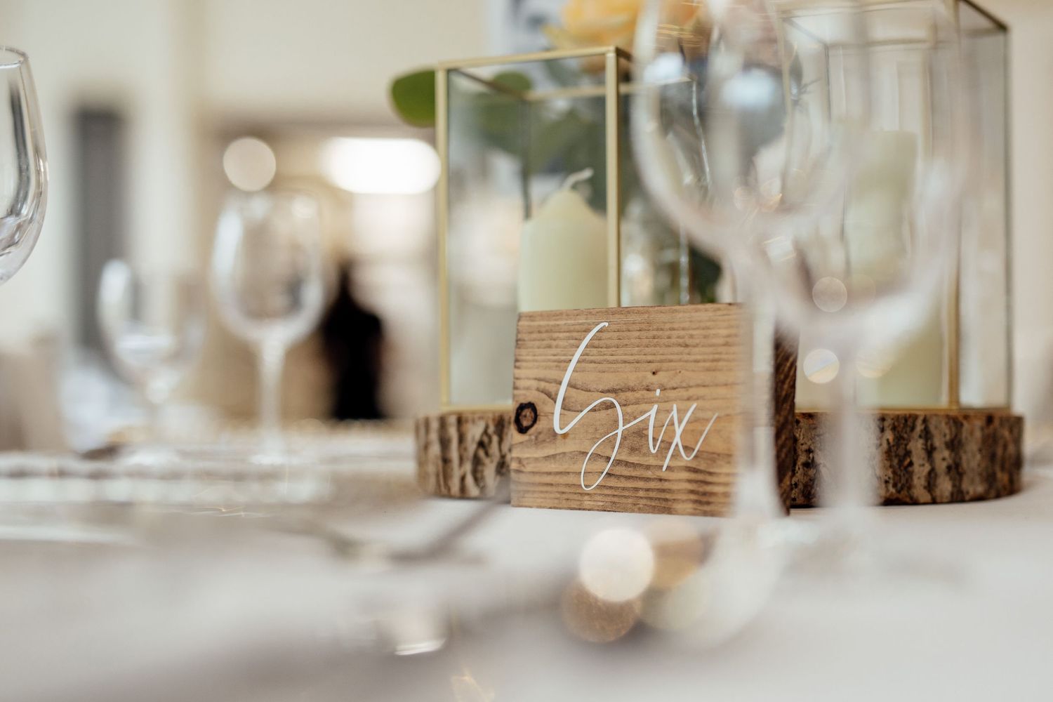 Elegant wedding table setting with rustic wooden 'love' sign and wine glasses.