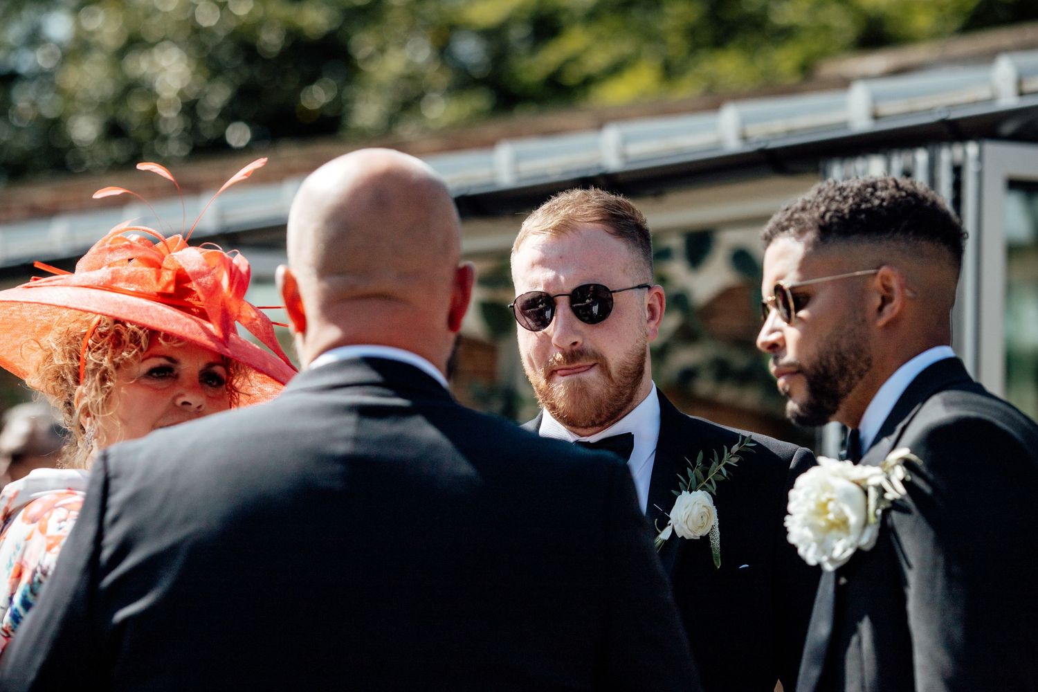 Wedding party mingles outdoors during a sunny daytime celebration.