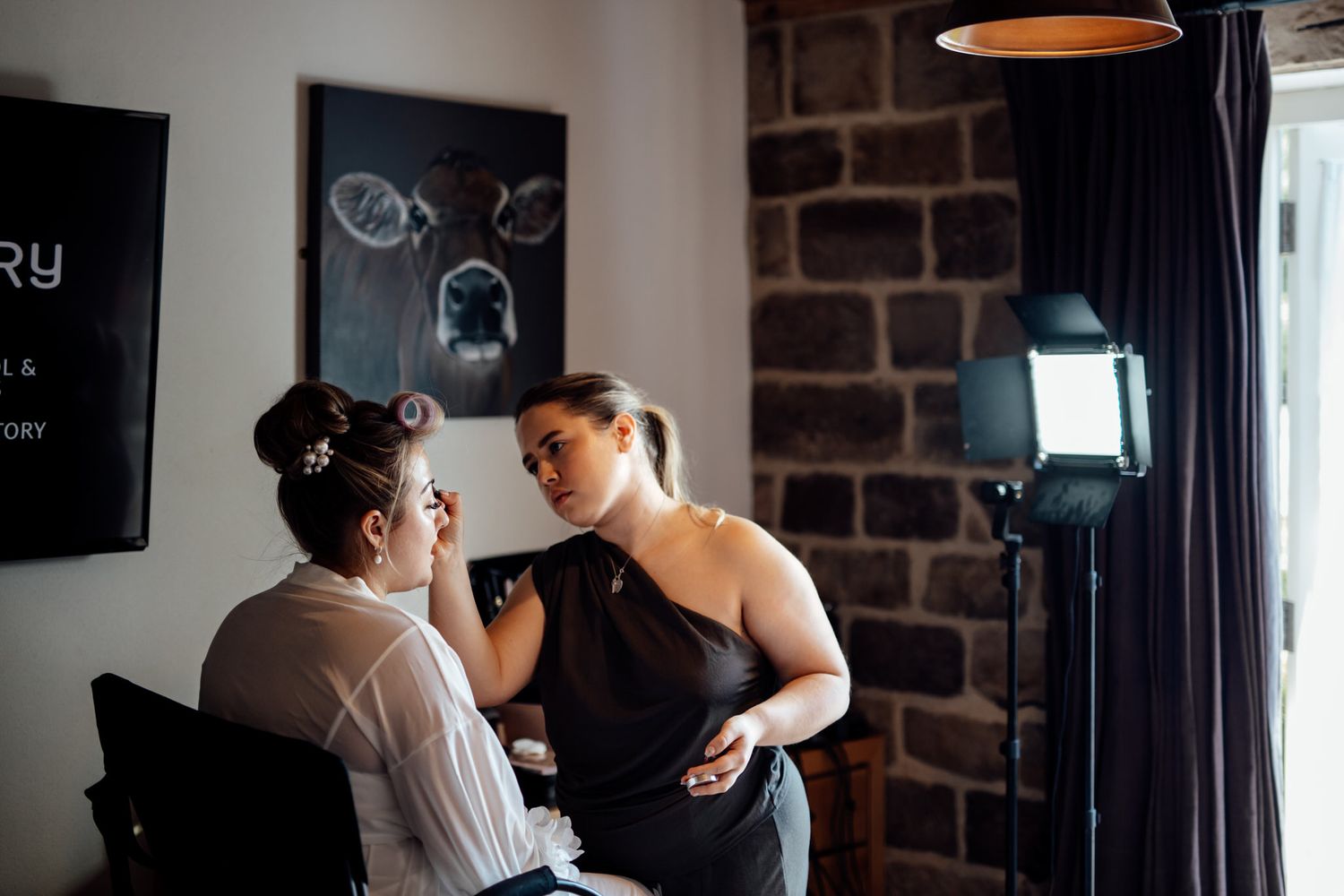 Wedding preparation scene in a dimly lit room with exposed brick walls.