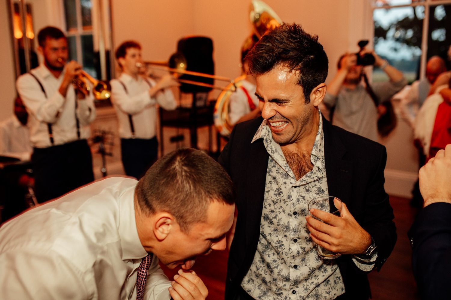 Party guests dancing and celebrating in formal attire at an indoor reception venue.