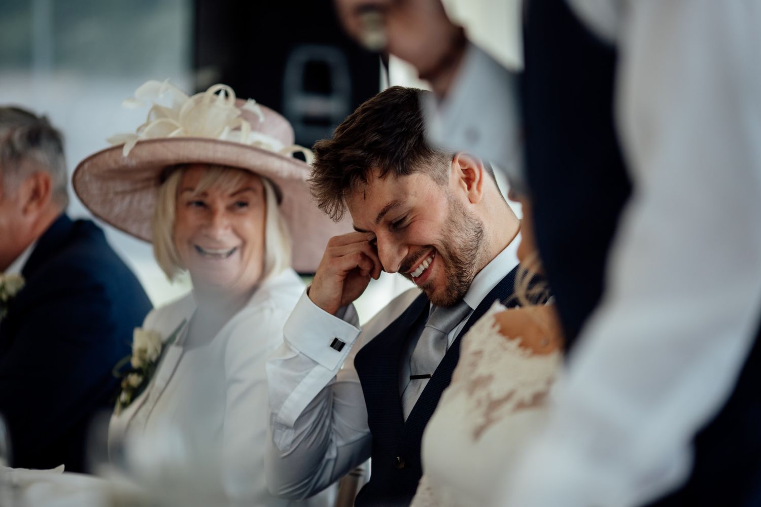 Candid moment of laughter during wedding reception speeches.