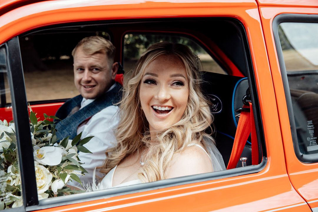 Classic bright orange vintage car used as wedding transportation.