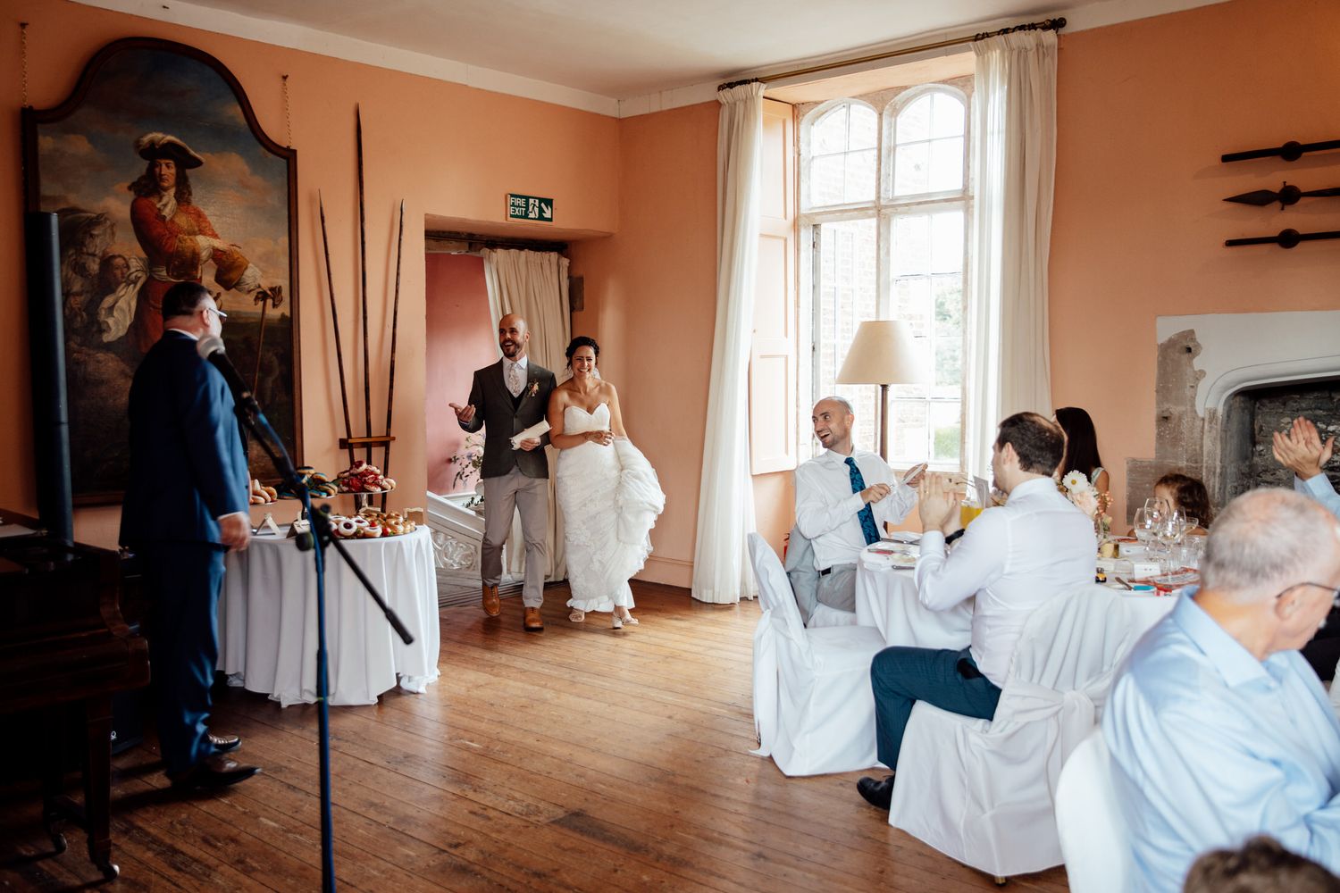A spacious wedding reception room with coral walls and large windows.