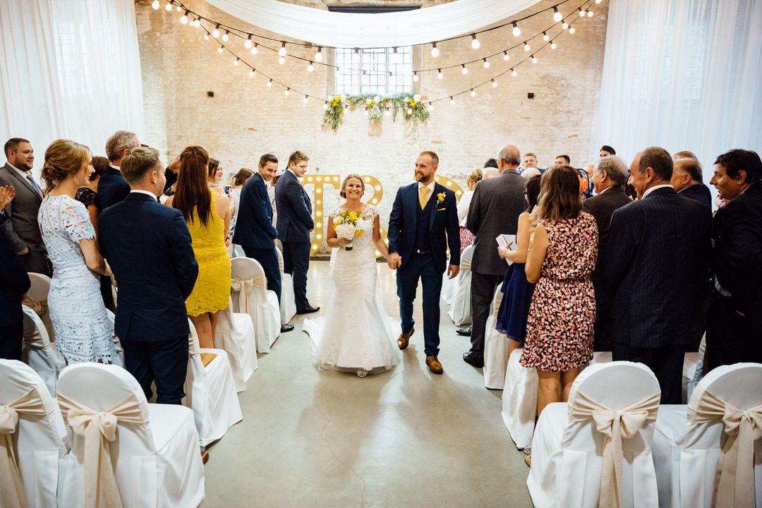 Elegant wedding reception venue with white chairs and twinkling string lights overhead.