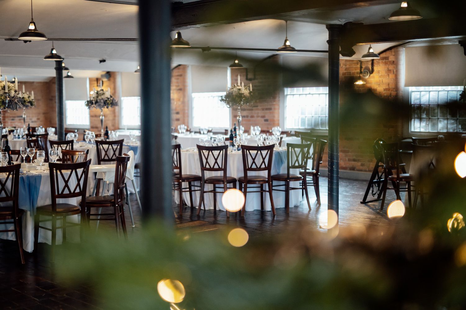 Interior of empty wedding venue with hanging lights and wooden dining tables.