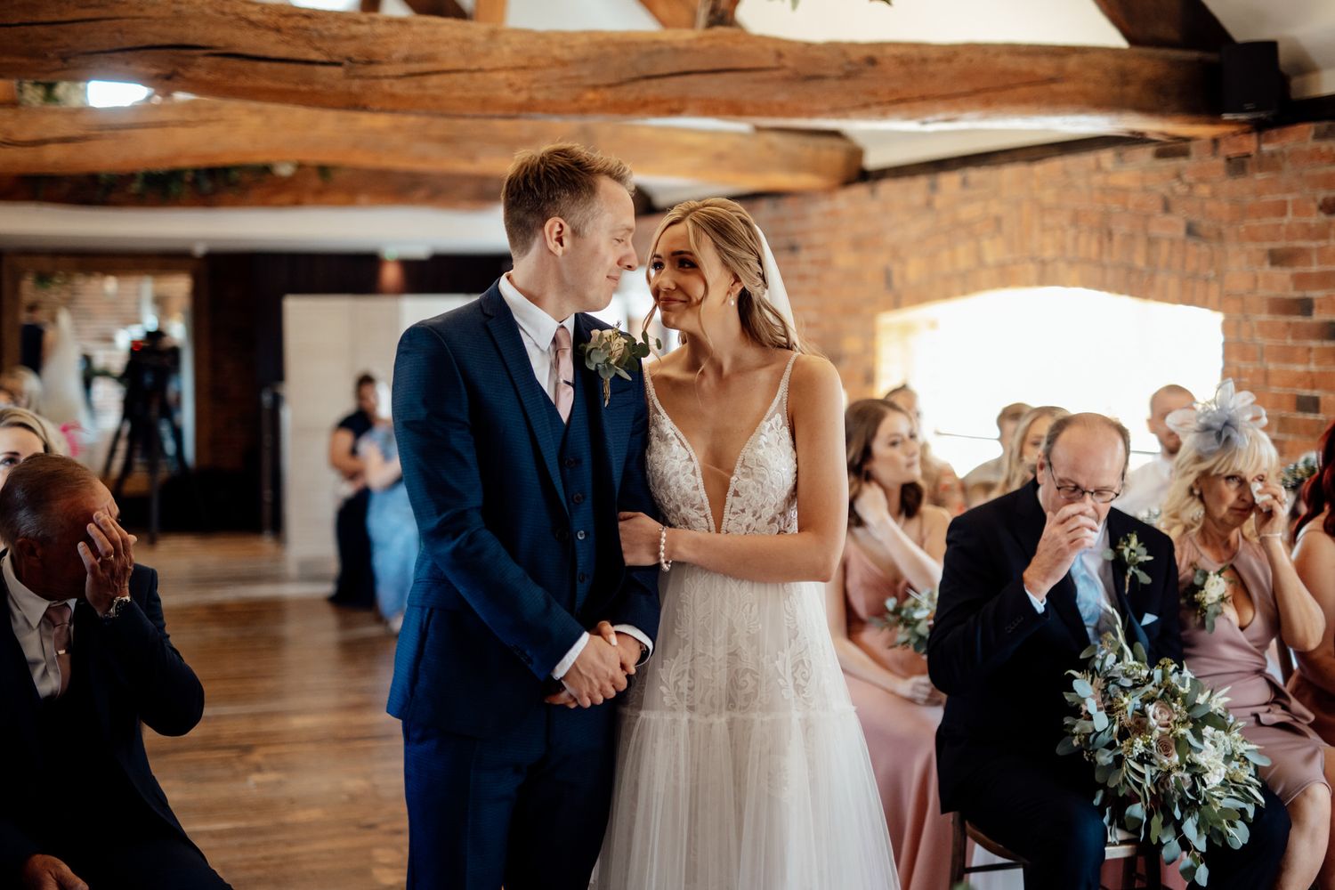 First dance moment captured in a rustic barn wedding venue with exposed beams.