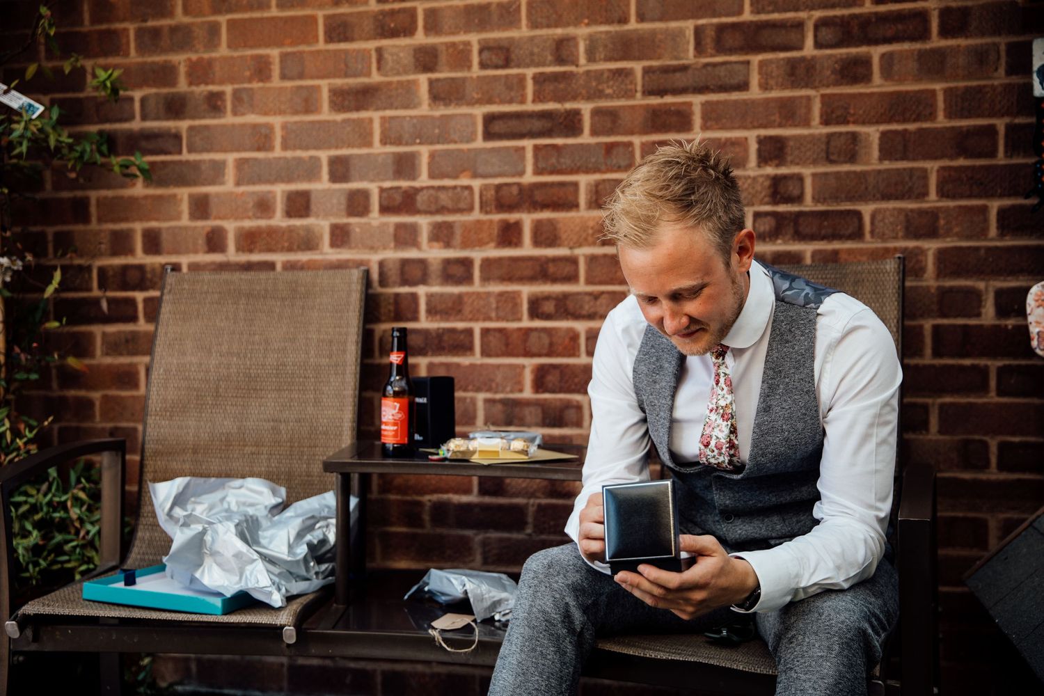 Groomsmen relaxing and checking phones while sitting on brick wall.