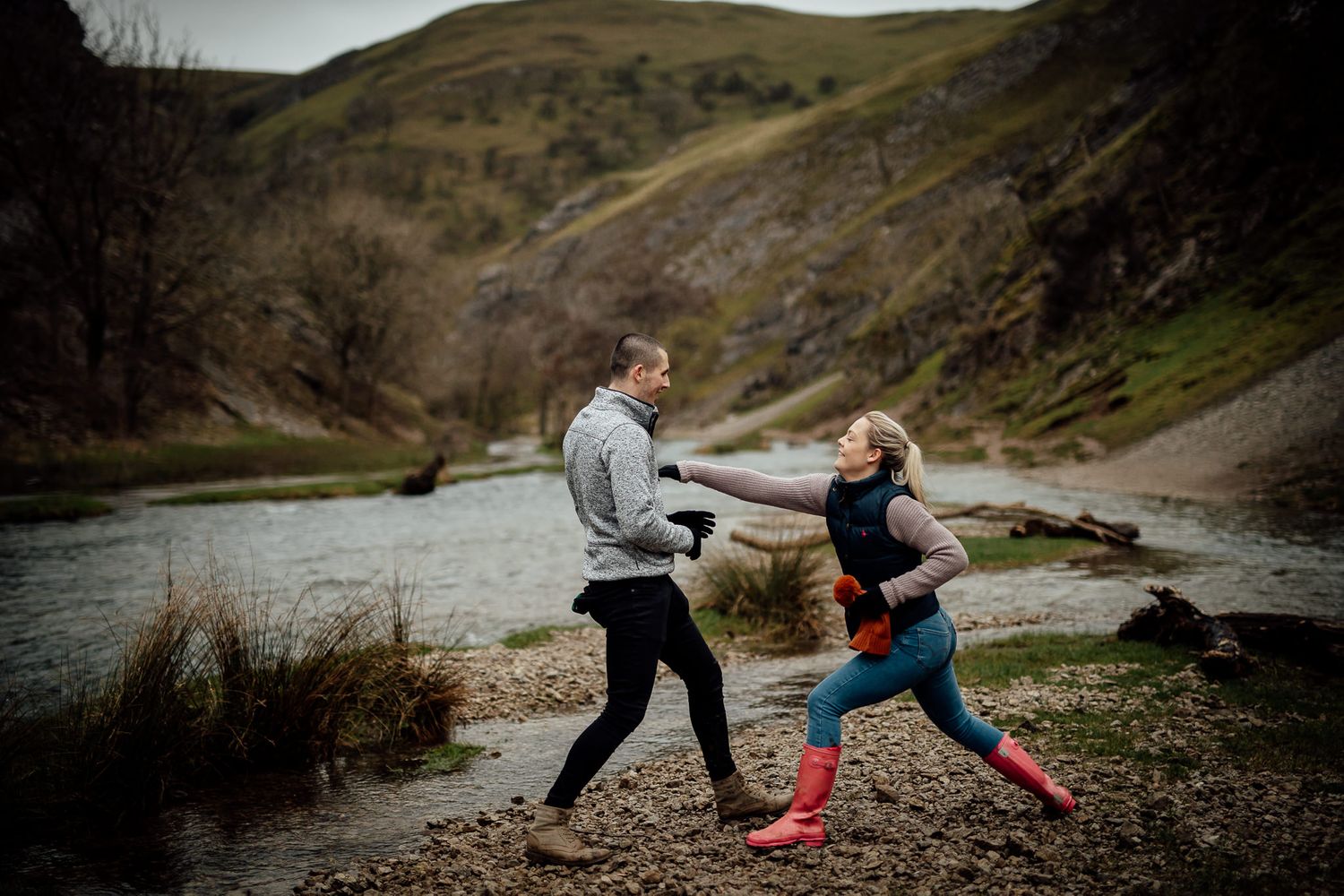 A playful couple interacts on a winding mountain path during an outdoor photo session.