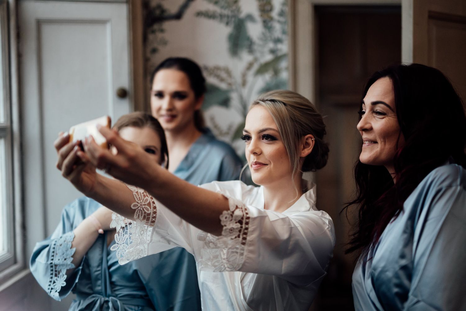 Bridesmaids in matching blue robes getting ready together before a wedding celebration.