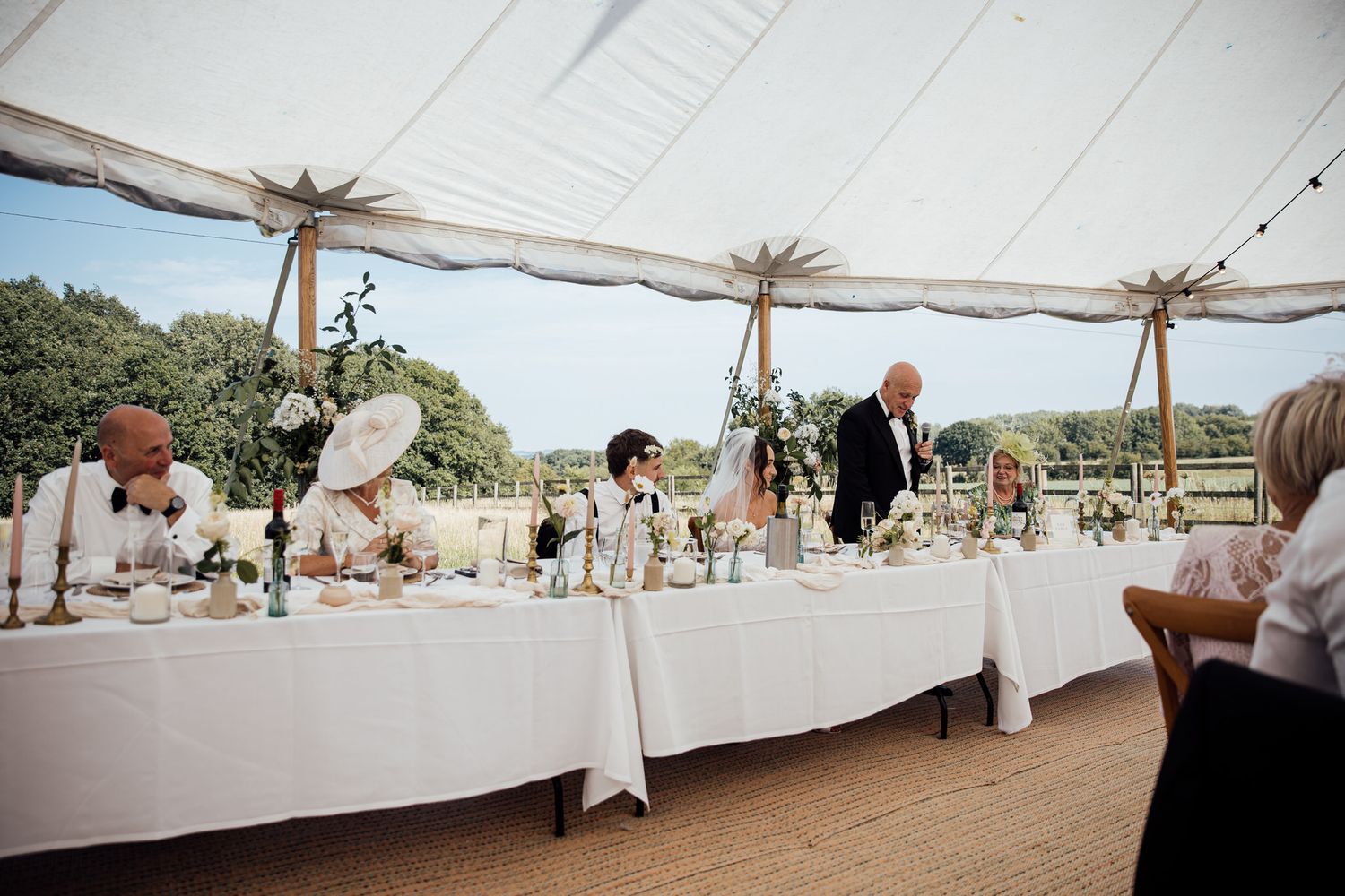 Large white wedding tent set up outdoors with tables and decorations.