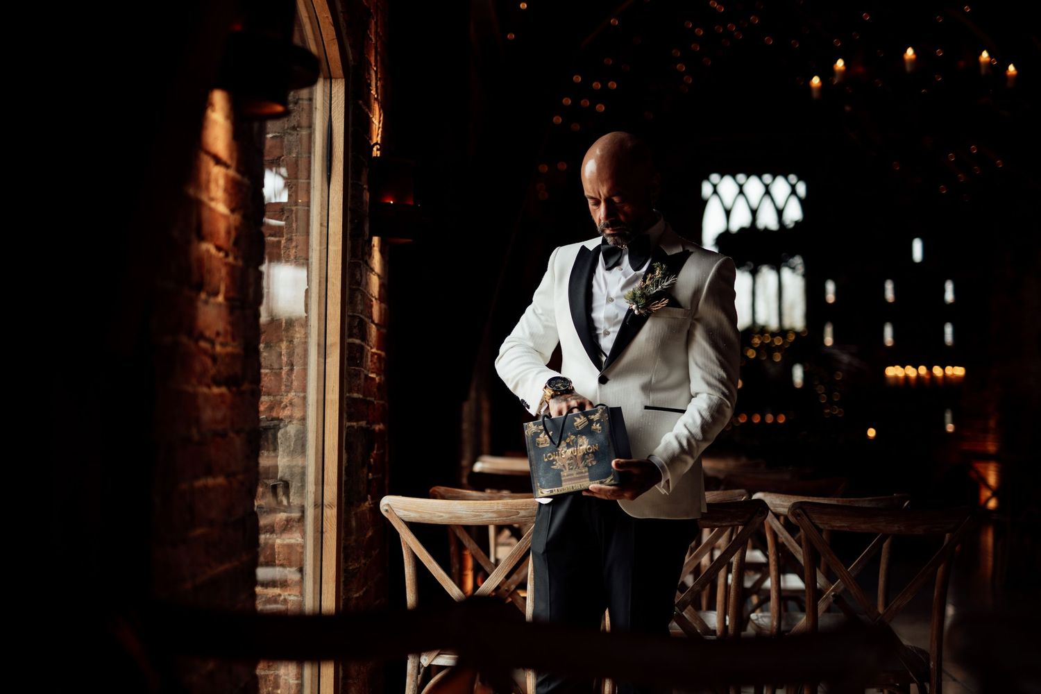 Bartender in white tuxedo jacket pouring drinks at an elegant venue with mood lighting.
