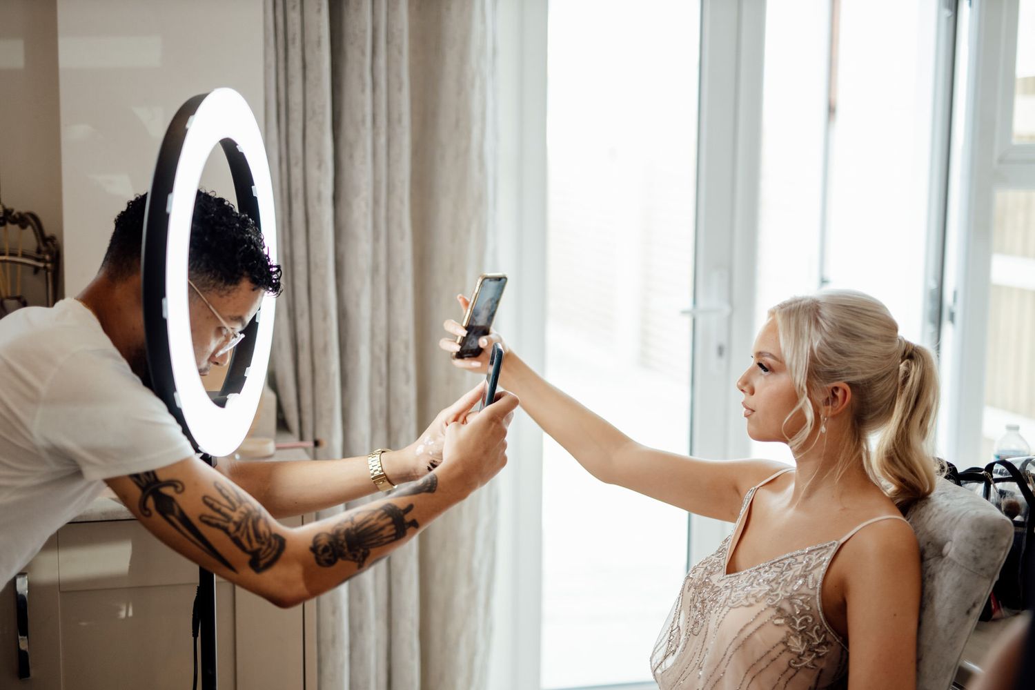 Getting ready moments captured in bright sunlit room with white curtains.