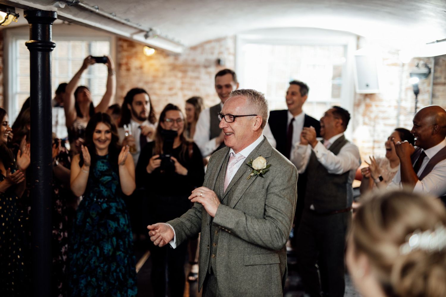 Wedding guests celebrating and dancing in an indoor reception space.