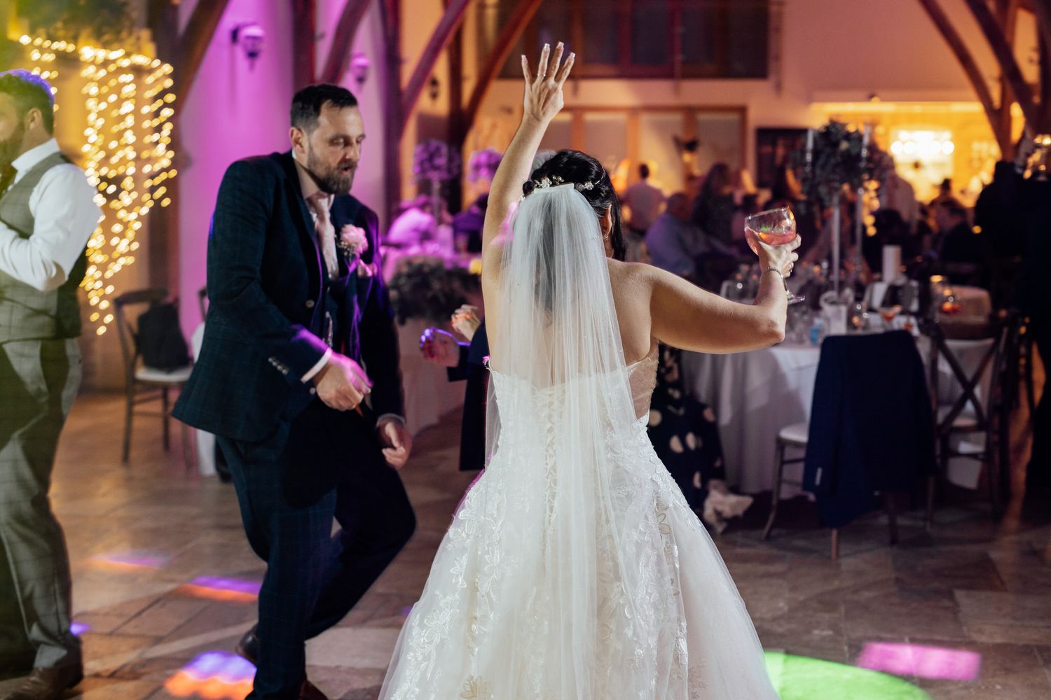 Wedding celebration in venue with purple lighting and string lights creating romantic ambiance.