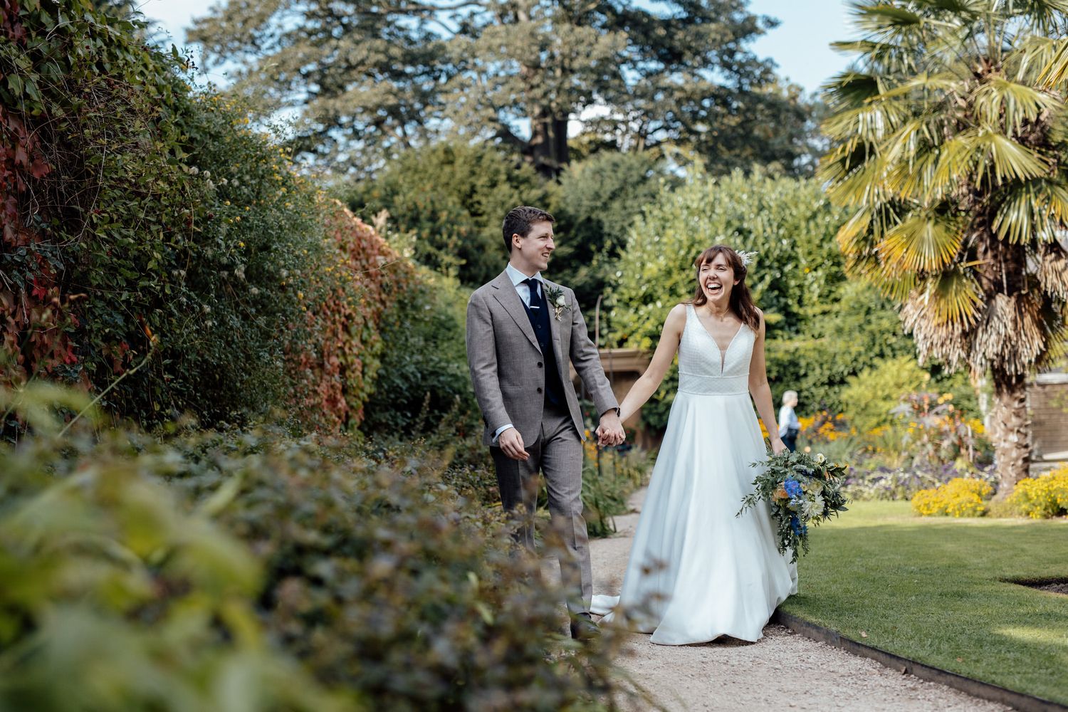 Couple taking romantic photos in a lush garden setting with palm trees and greenery.