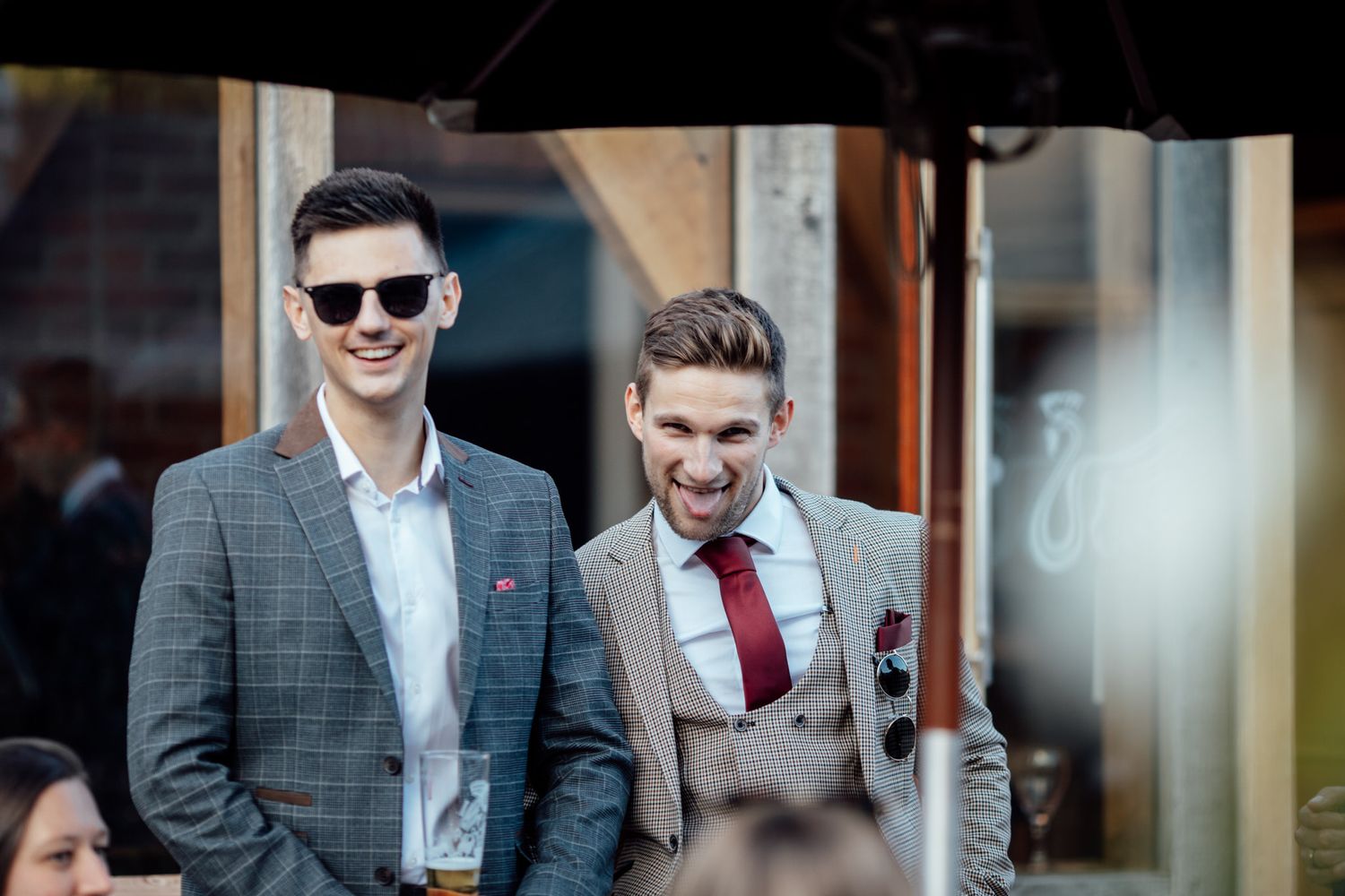 Groomsmen in formal suits walking and smiling during a wedding celebration.
