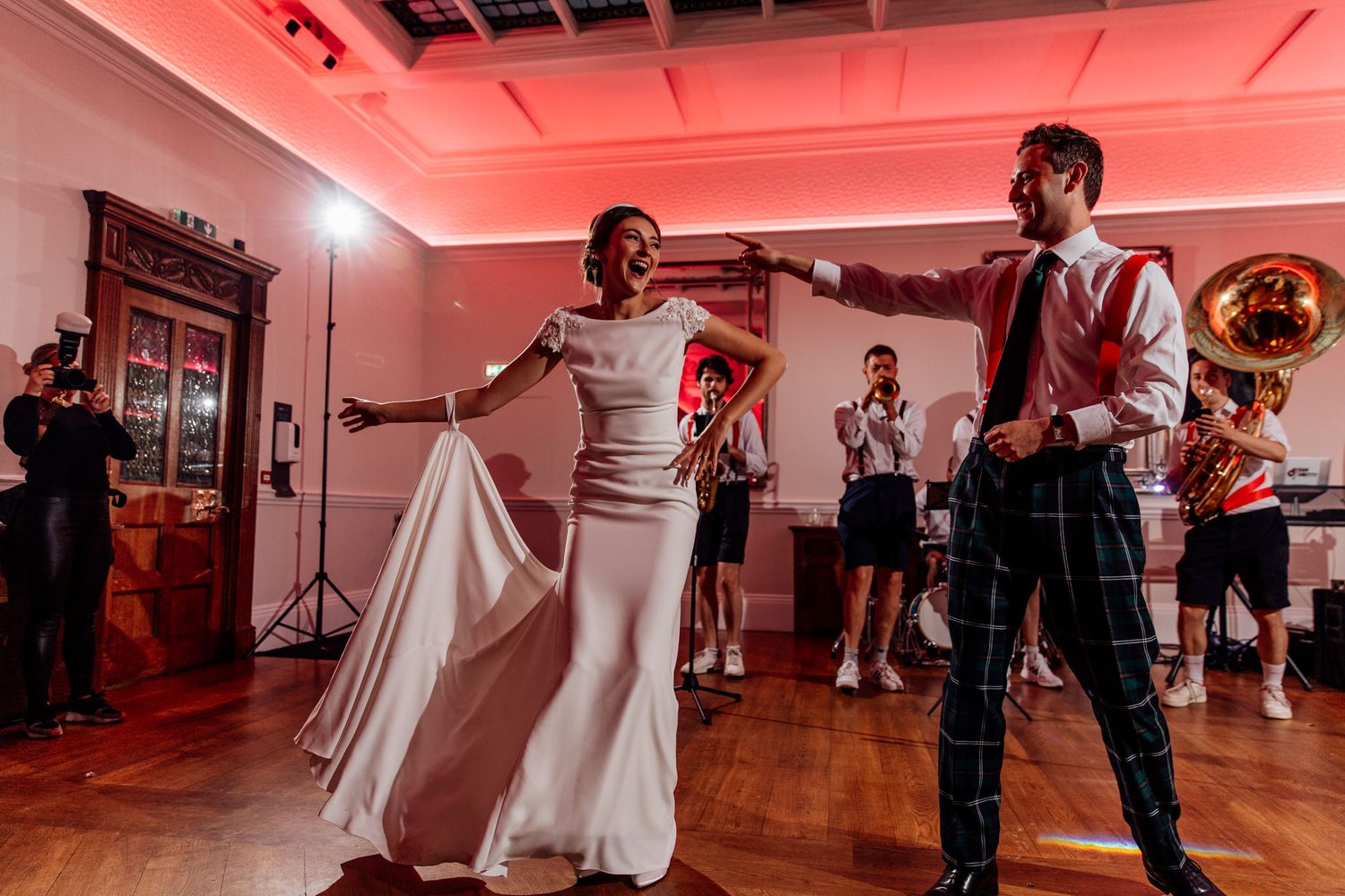 Lively dance floor scene with guests celebrating under red mood lighting.