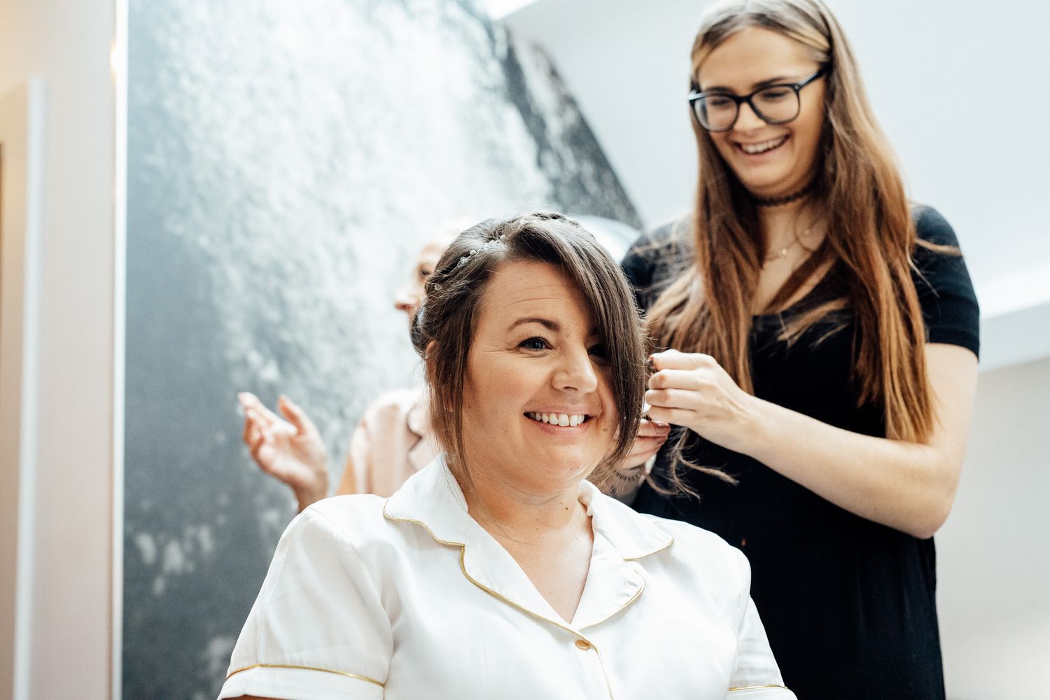 Wedding preparation scene with stylist working on bridal hair.