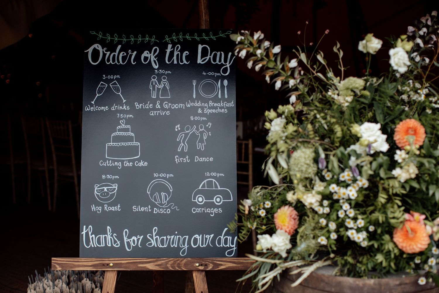 Chalkboard wedding signs display menu items and decorative drawings at a rustic reception.
