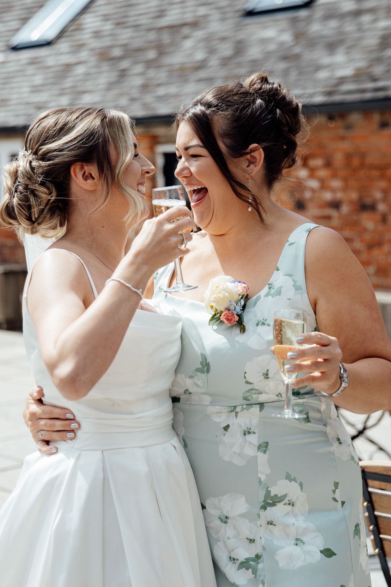 Bridesmaids in white and floral dresses sharing joyful laughter together.