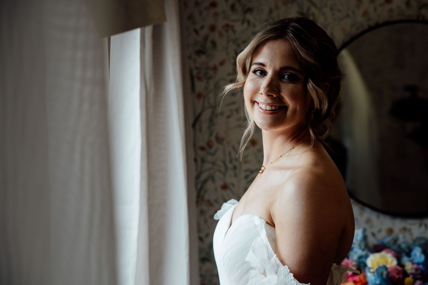 A wedding party poses for portraits in front of a white wall with elegant details.