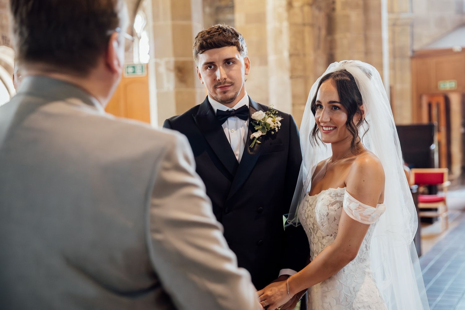 Elegant church wedding ceremony with stone archways and stained glass windows.