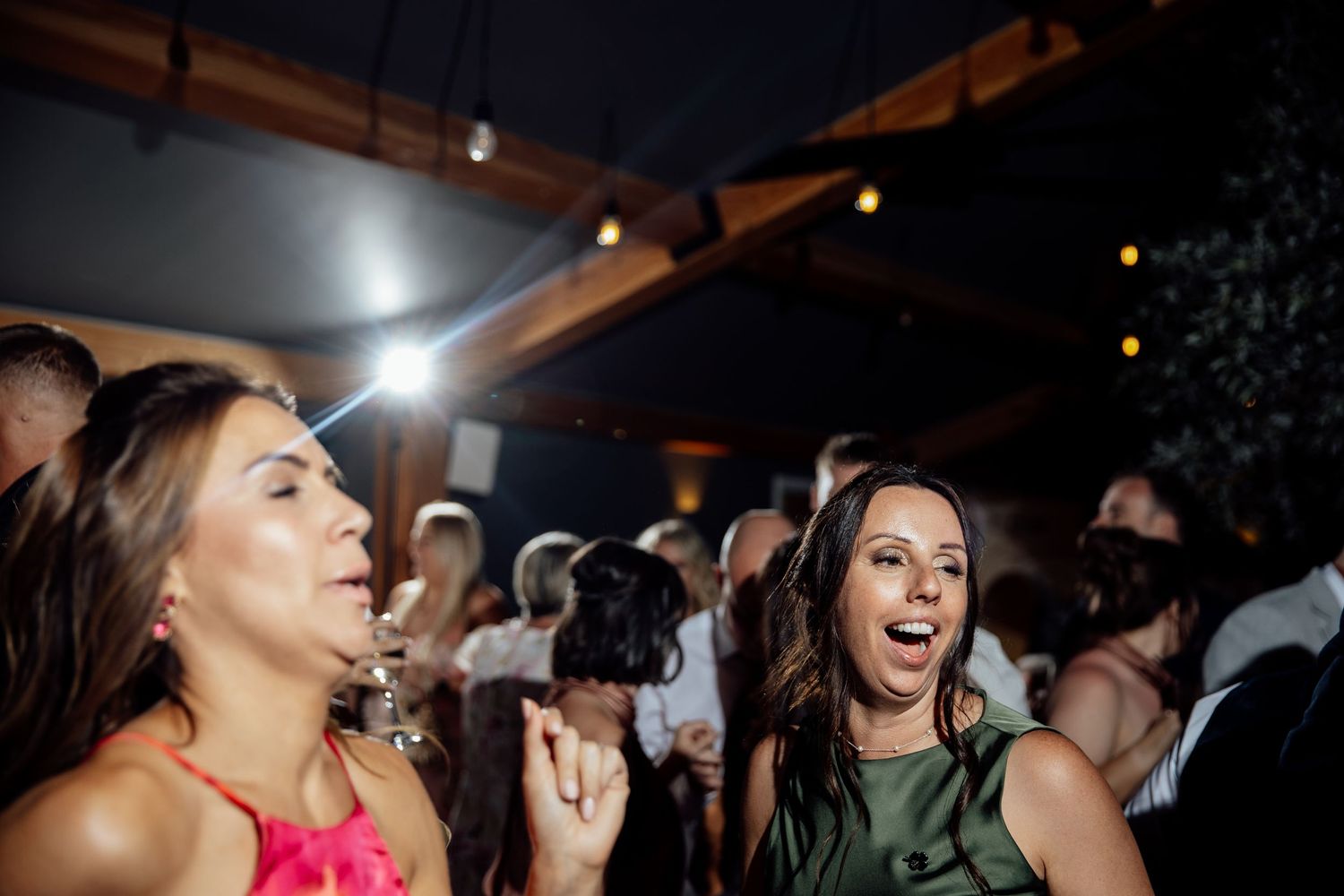 Energetic dancing and celebrations during a dimly lit wedding reception.
