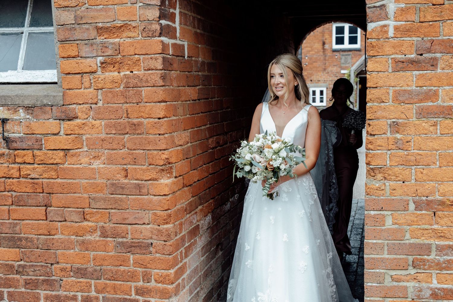 Couple poses against red brick wall exterior on their wedding day.
