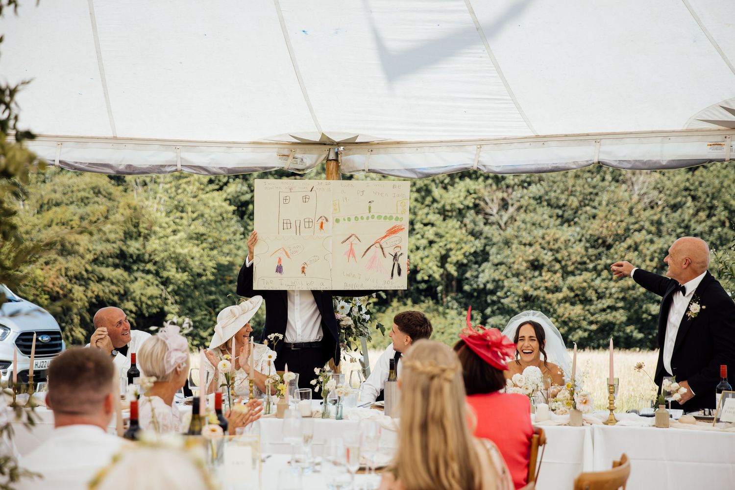 Wedding reception setup with white tents and outdoor dining arrangements in a garden setting.
