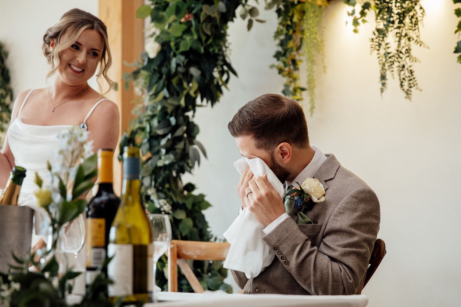 Wedding speeches and toasts in an elegant indoor venue with hanging greenery.