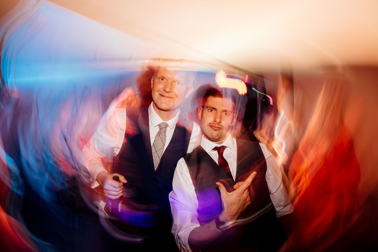 Wedding party members dancing with creative lighting effects and motion blur.