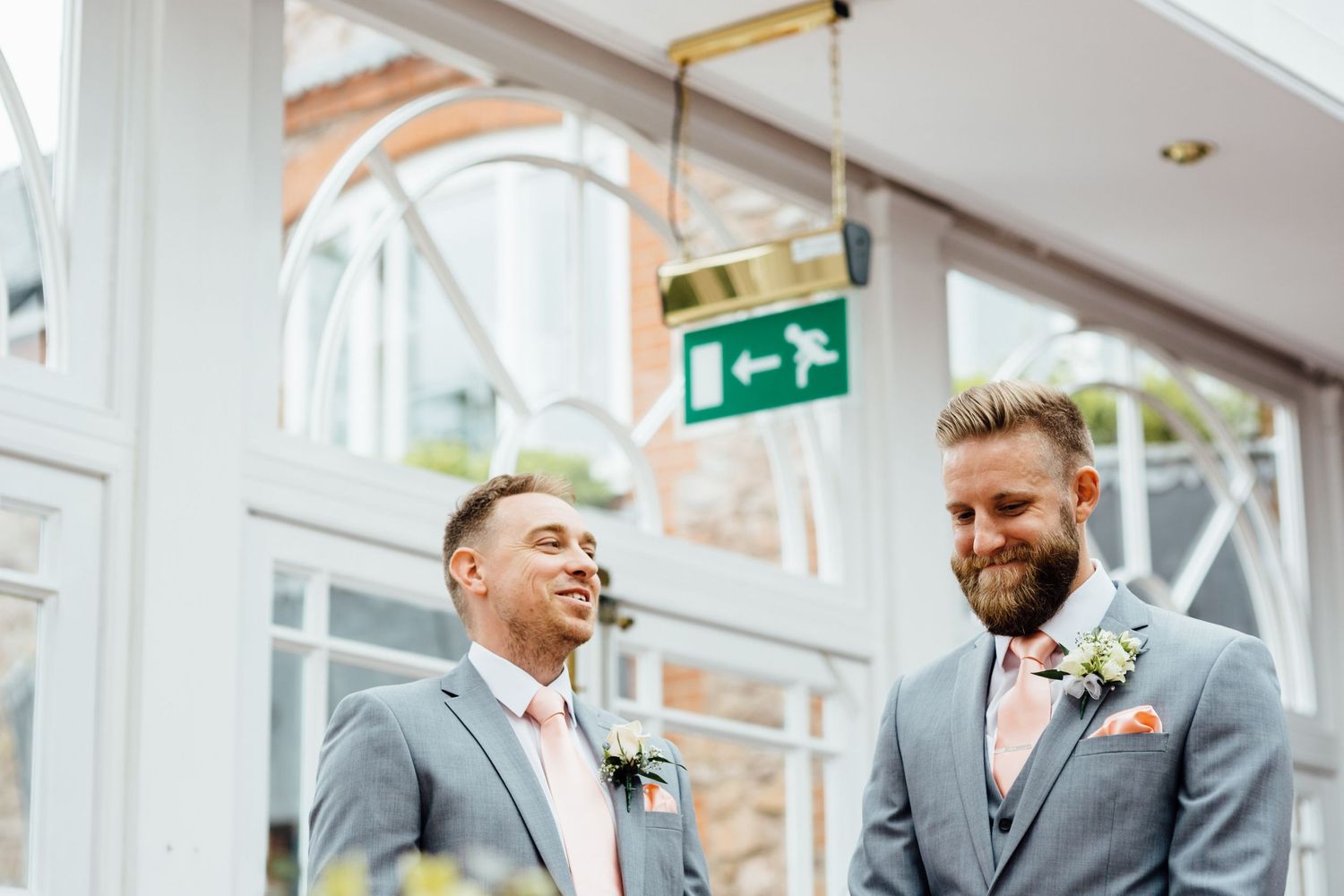 Wedding party gathered in bright indoor venue with large windows and modern decor.