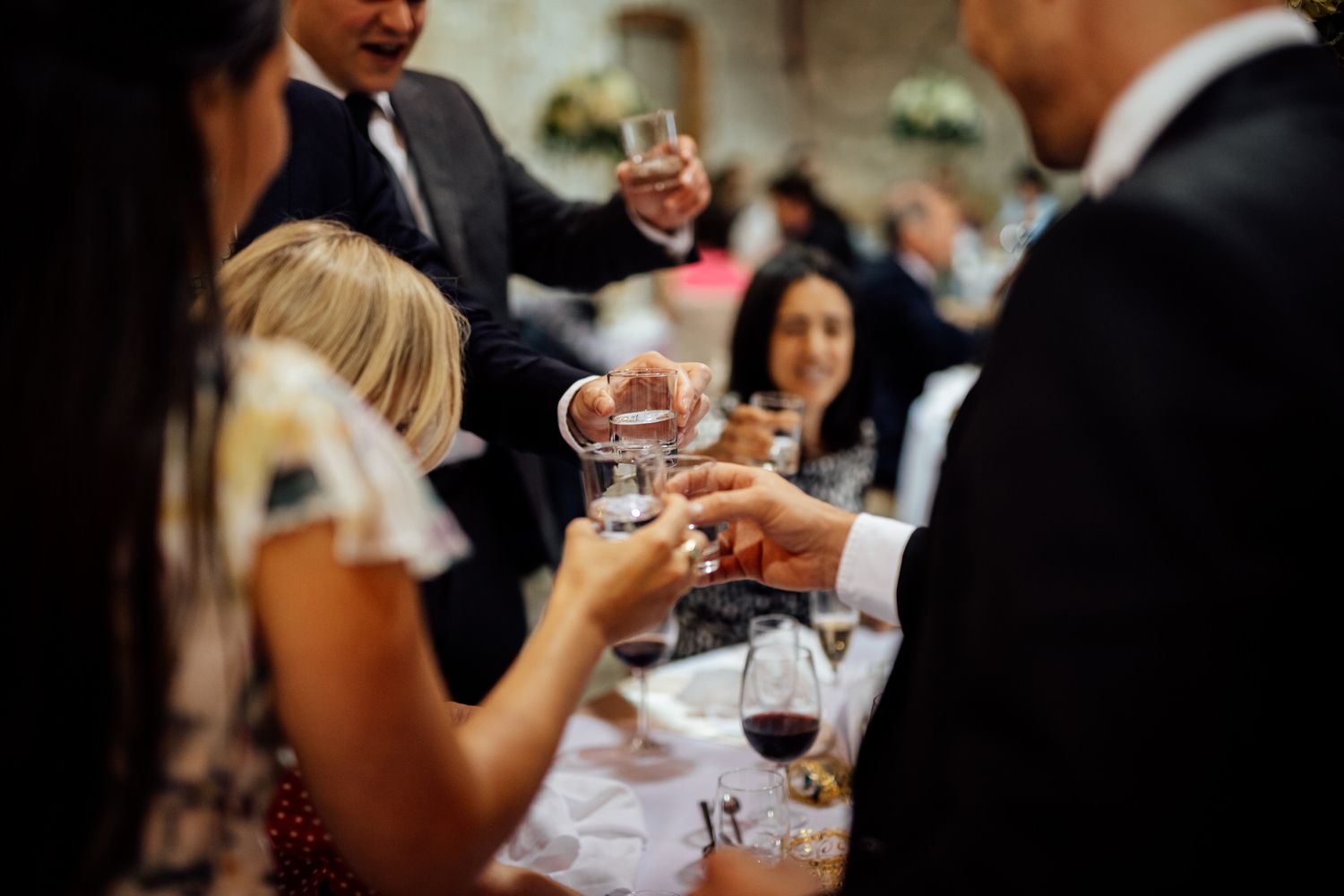 Wedding reception guests enjoying wine and conversation at elegantly set tables.