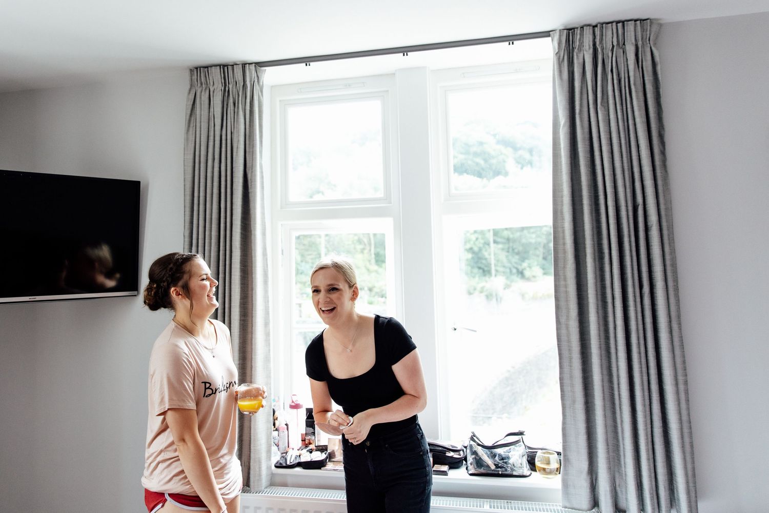 Getting ready scene in bright white room with gray curtains and natural light.