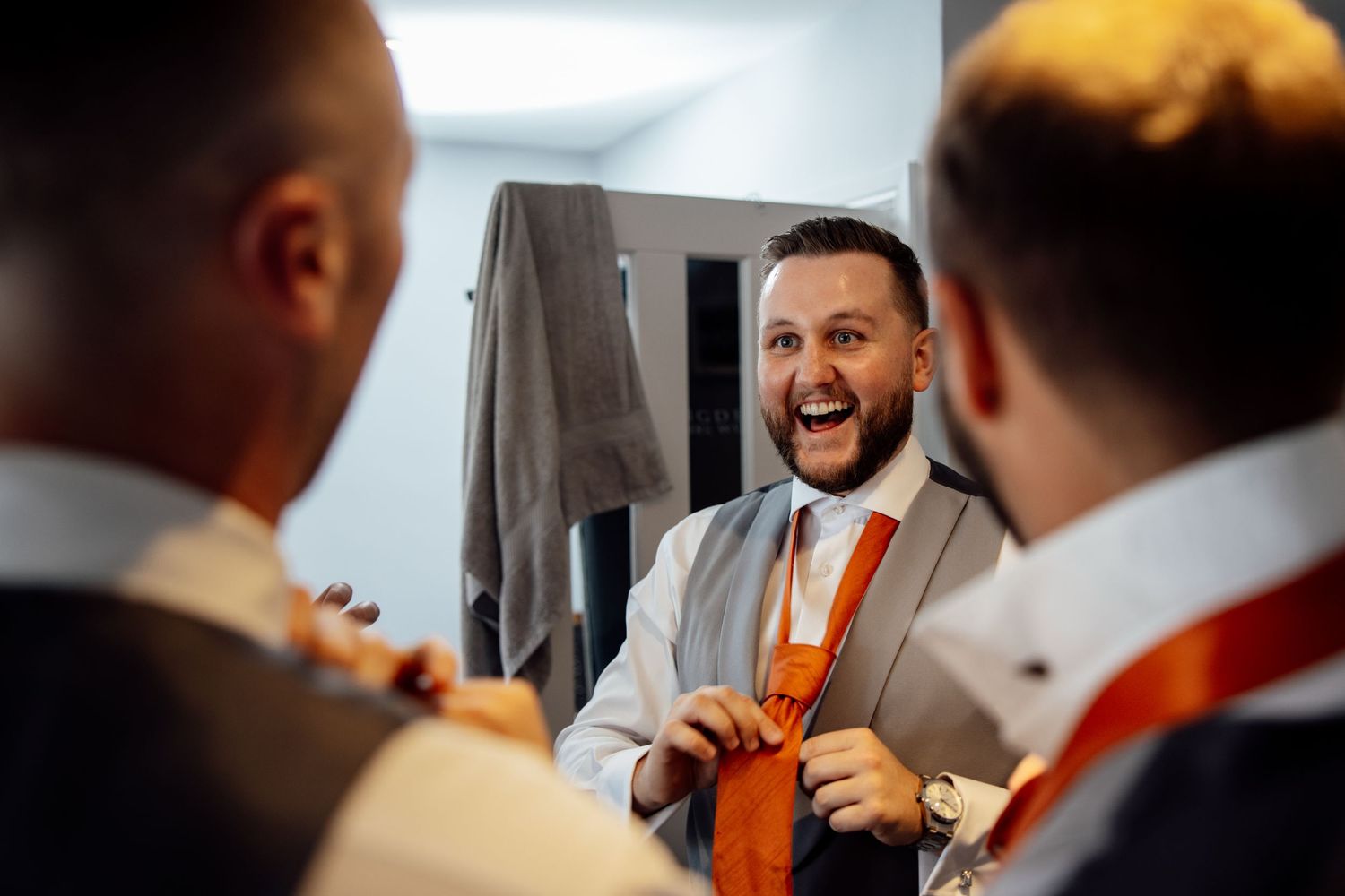 Guests in formal attire share laughs during an indoor wedding celebration.