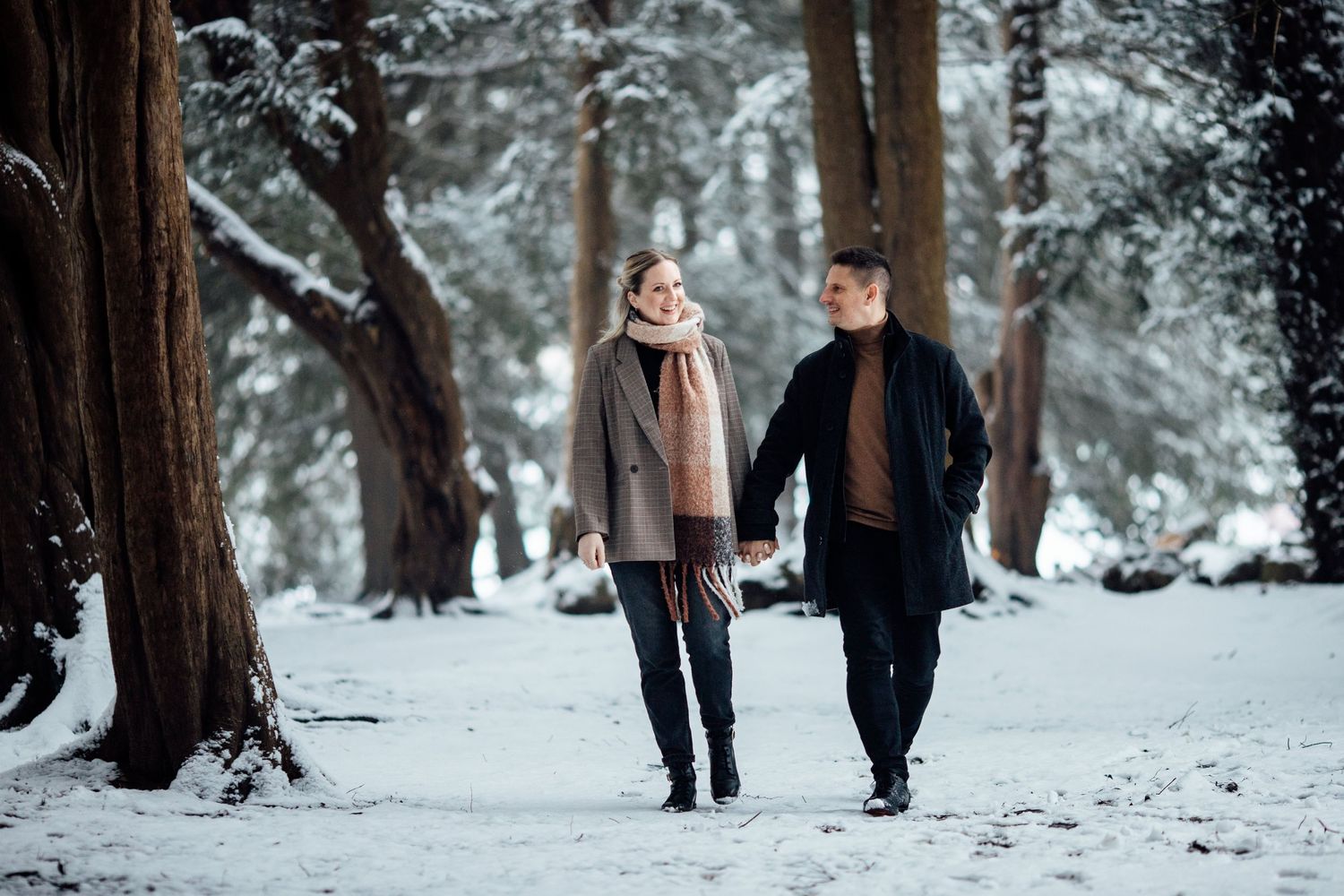 Couple strolling together through snow-covered forest path.