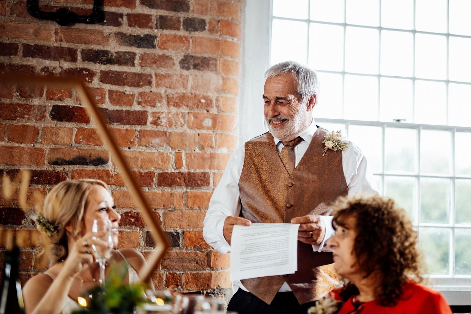 Wedding reception scene in an industrial venue with exposed brick and natural lighting.