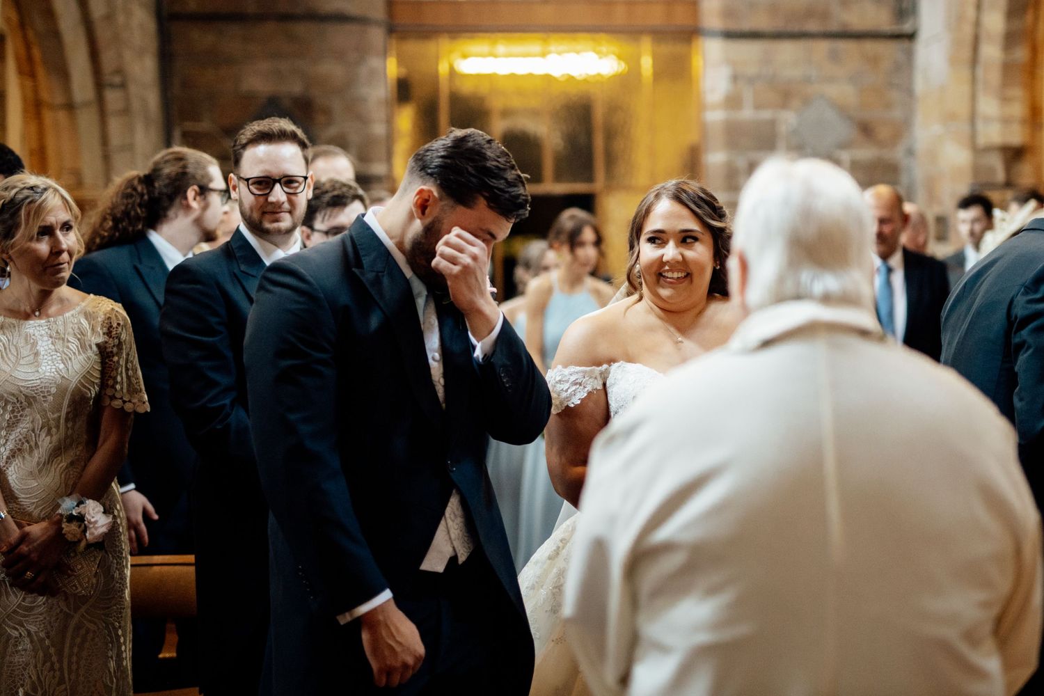 Wedding celebration inside historic church with warm lighting and stone archways.
