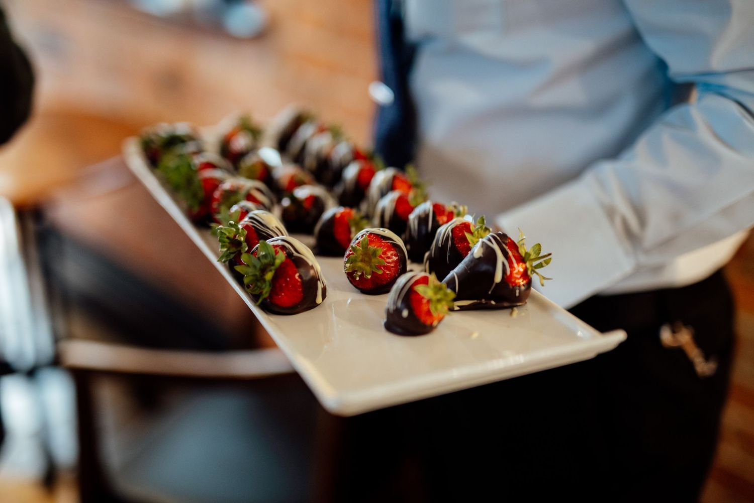 Elegant display of chocolate covered strawberries on silver platters.