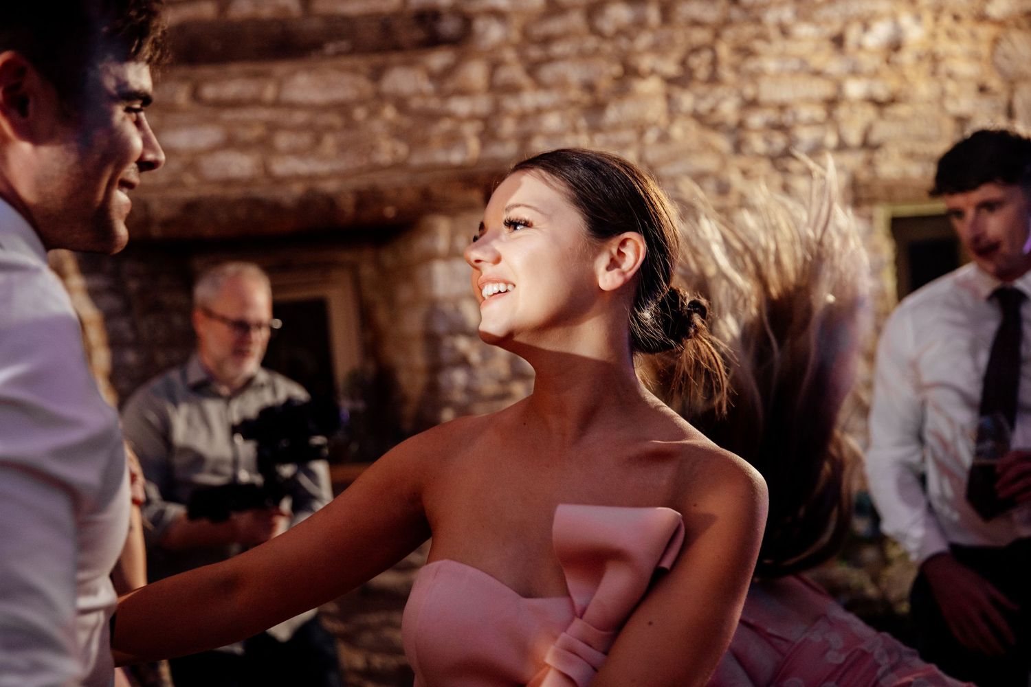 Guest dancing energetically at wedding reception in rustic stone venue.