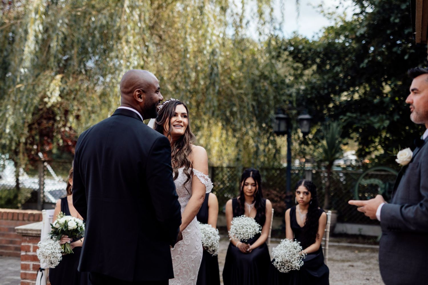 Outdoor wedding ceremony with willow trees and formal attire.