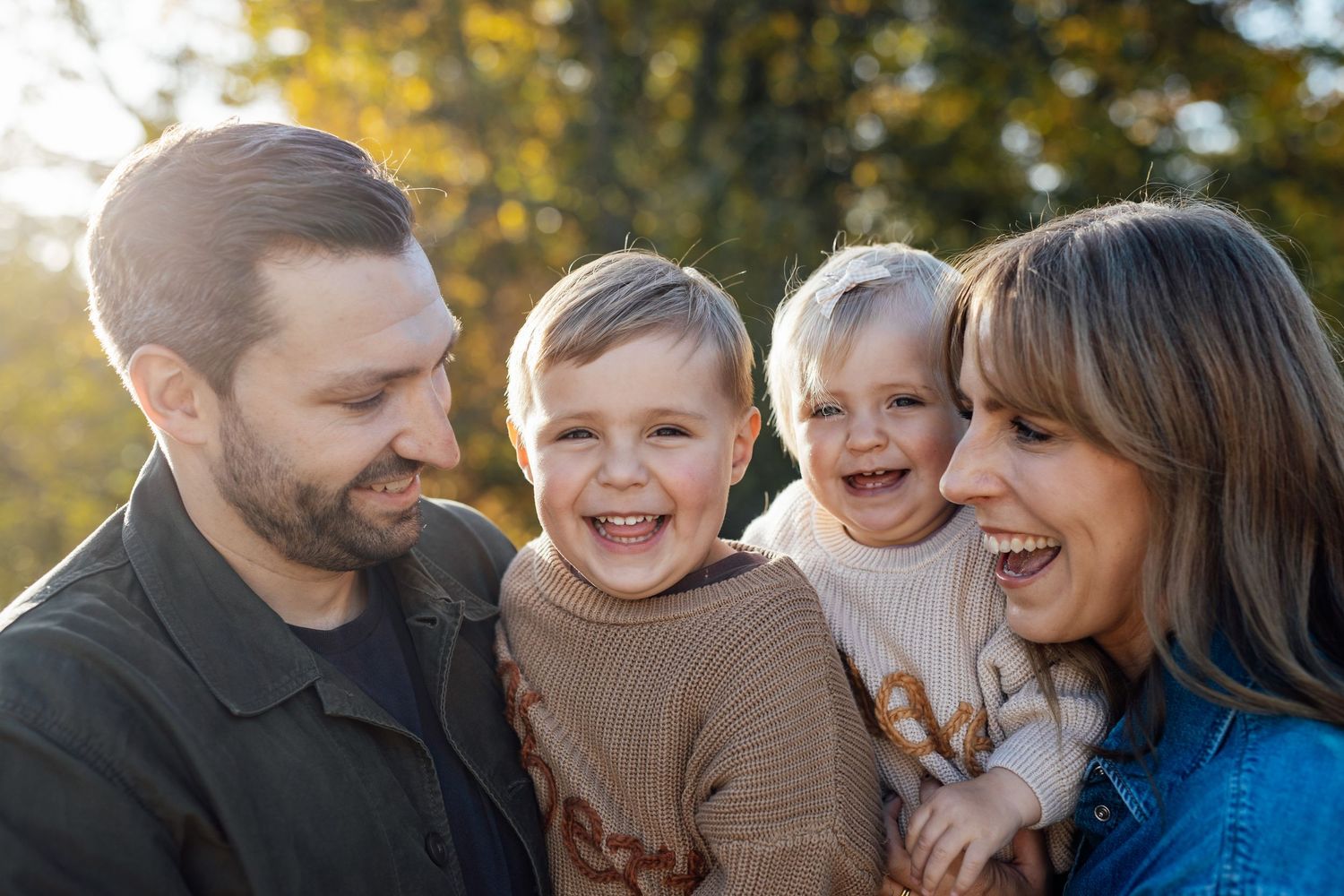 Candid outdoor family portrait with warm autumn lighting and natural expressions.