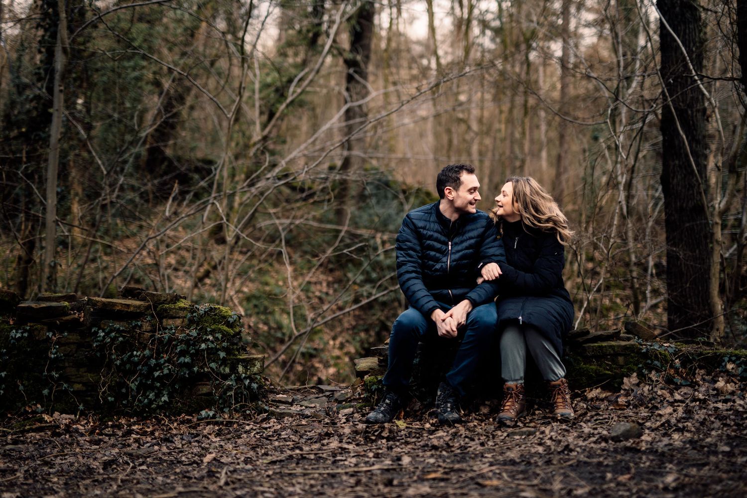 Two people share romantic moments along a wooded path during golden hour.