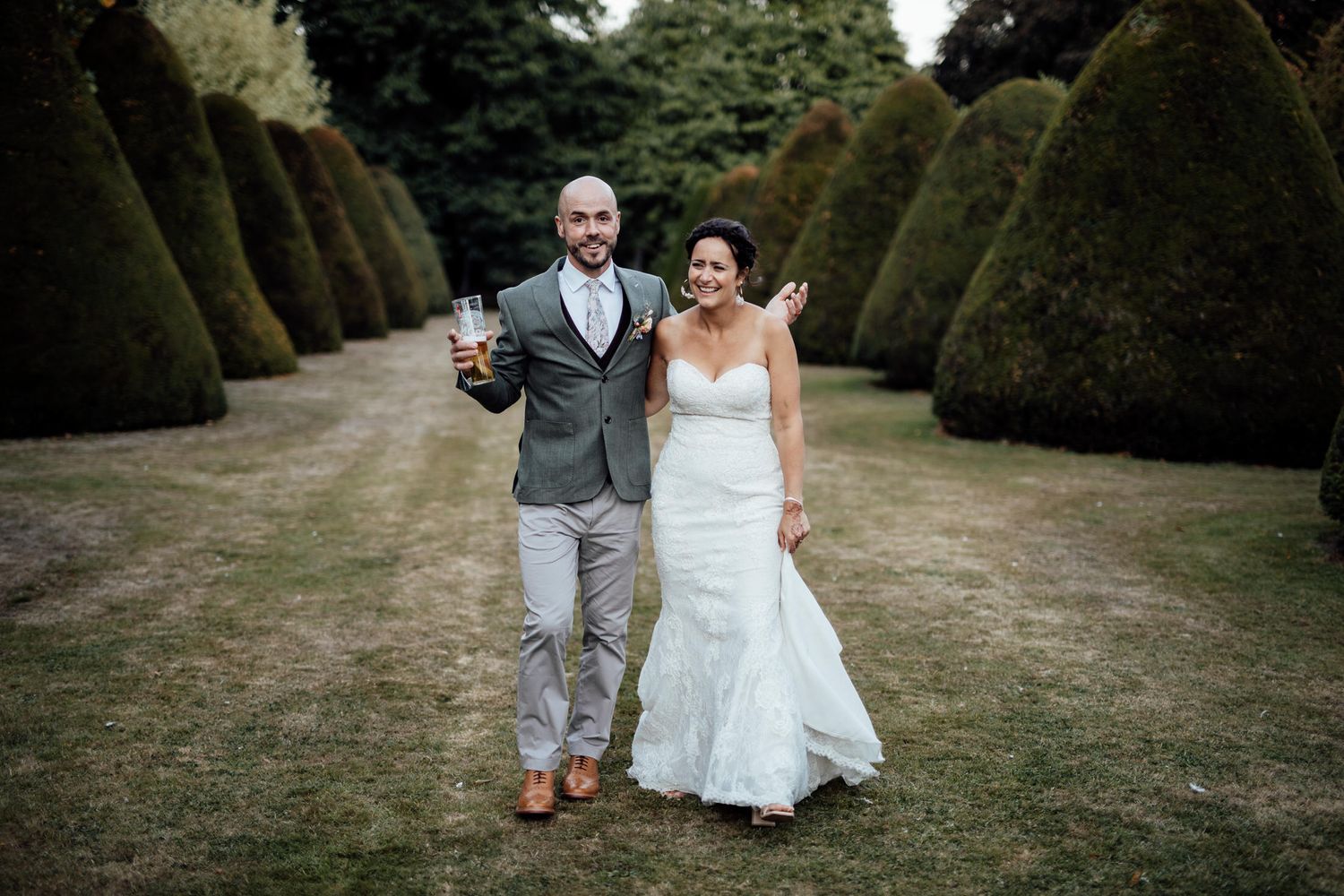 Couple walks along a manicured garden path surrounded by tall hedges.