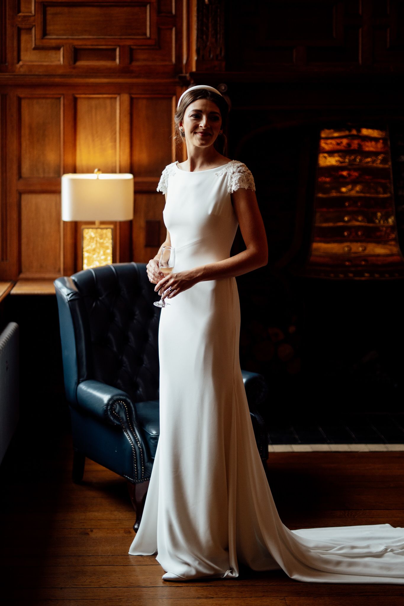 Classic white wedding gown photographed in a warmly lit room with wooden paneling.