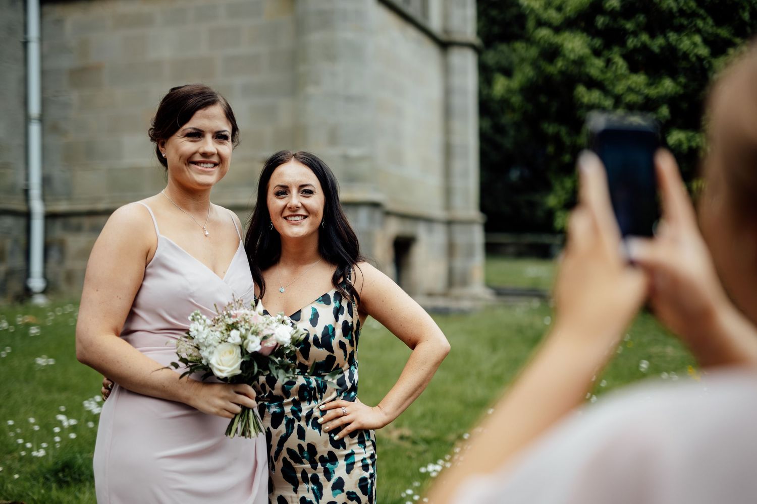 Wedding guests gathered on church lawn celebrating with joyful expressions.