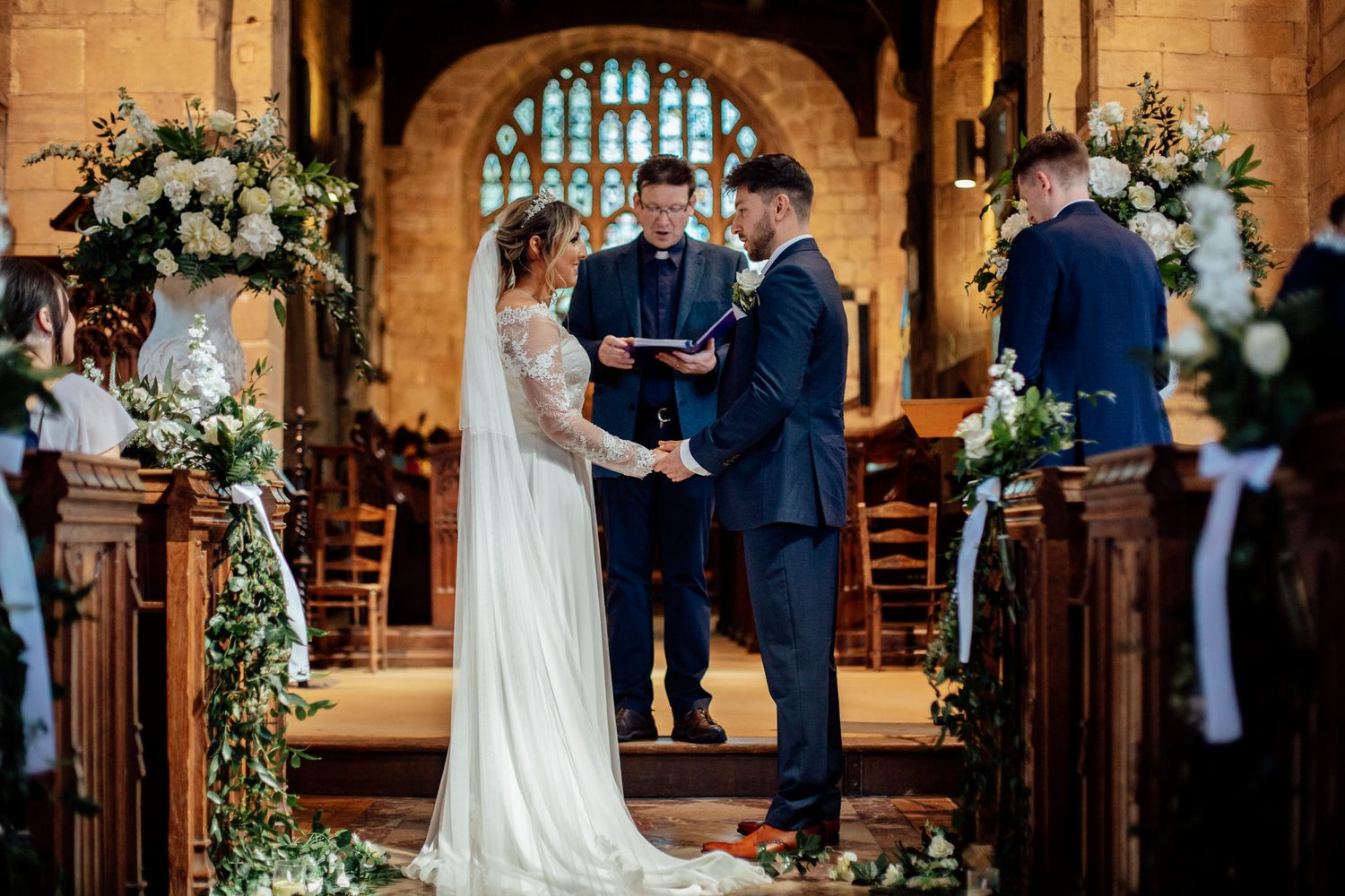 Wedding ceremony in a historic church with stone architecture and floral decorations.
